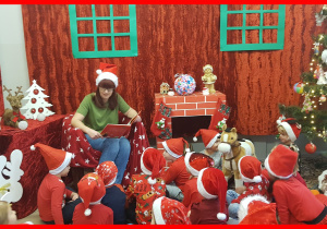 Dzieci z Biedronek w pokoju Świętego Mikołaja słuchają jak pani Mirka czyta bajkę